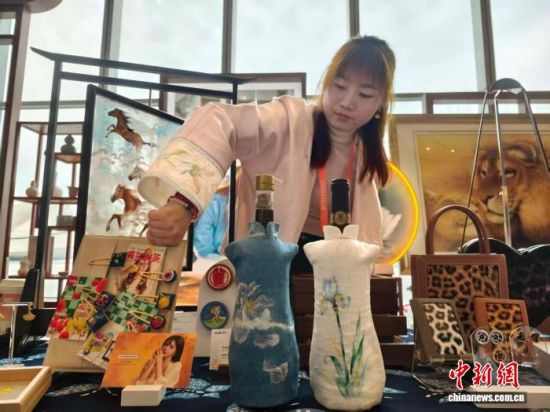 昌妮携手蜡染扎染非遗代表性传承人冯灿制作的刺绣旗袍红酒套亮相第七届中法文化论坛非遗展。中新网记者 唐小晴 摄 昌妮携手蜡染扎染非遗代表性传承人冯灿制作的刺绣旗袍红酒套亮相第七届中法文化论坛非遗展。中新网记者 唐小晴 摄
